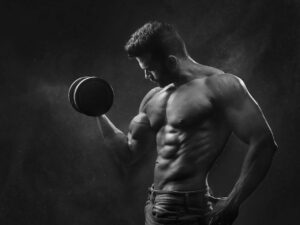 A muscular man performing a bicep curl with a dumbbell, surrounded by a misty atmosphere in black and white.